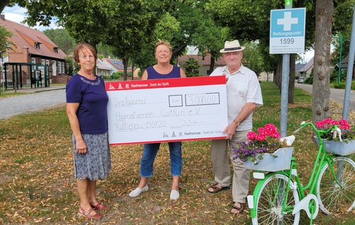 Ingetraut Prill, Ramona Schröder und Klaus Hartmann (v.l.) nehmen den symbolischen Scheck in Höhe von 3.000 Euro auf dem Göttliner Dorfplatz entgegen.